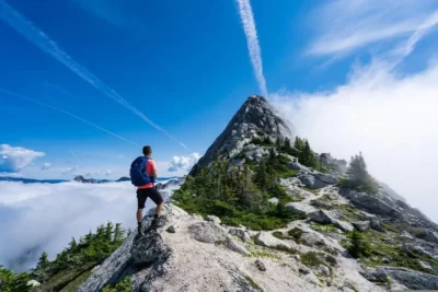 Wanderer auf dem Grat blickt zur Bergspitze. Toller Himmel mit Kondenswasser-Spuren von Flugzeugen